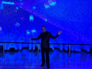 Corporate Mentalist Adam Stone Inside the Planet Word Museum in Washington Dc Surrounded by Words Projected on the Walls with Moving Spotlights Highlighting Different Words Throughout the Exhibit